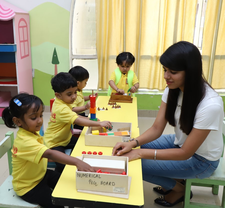 Teacher teaching Children Montessori ring stacker activity, putting rings on a tower at Crayons Play School Ranchi
